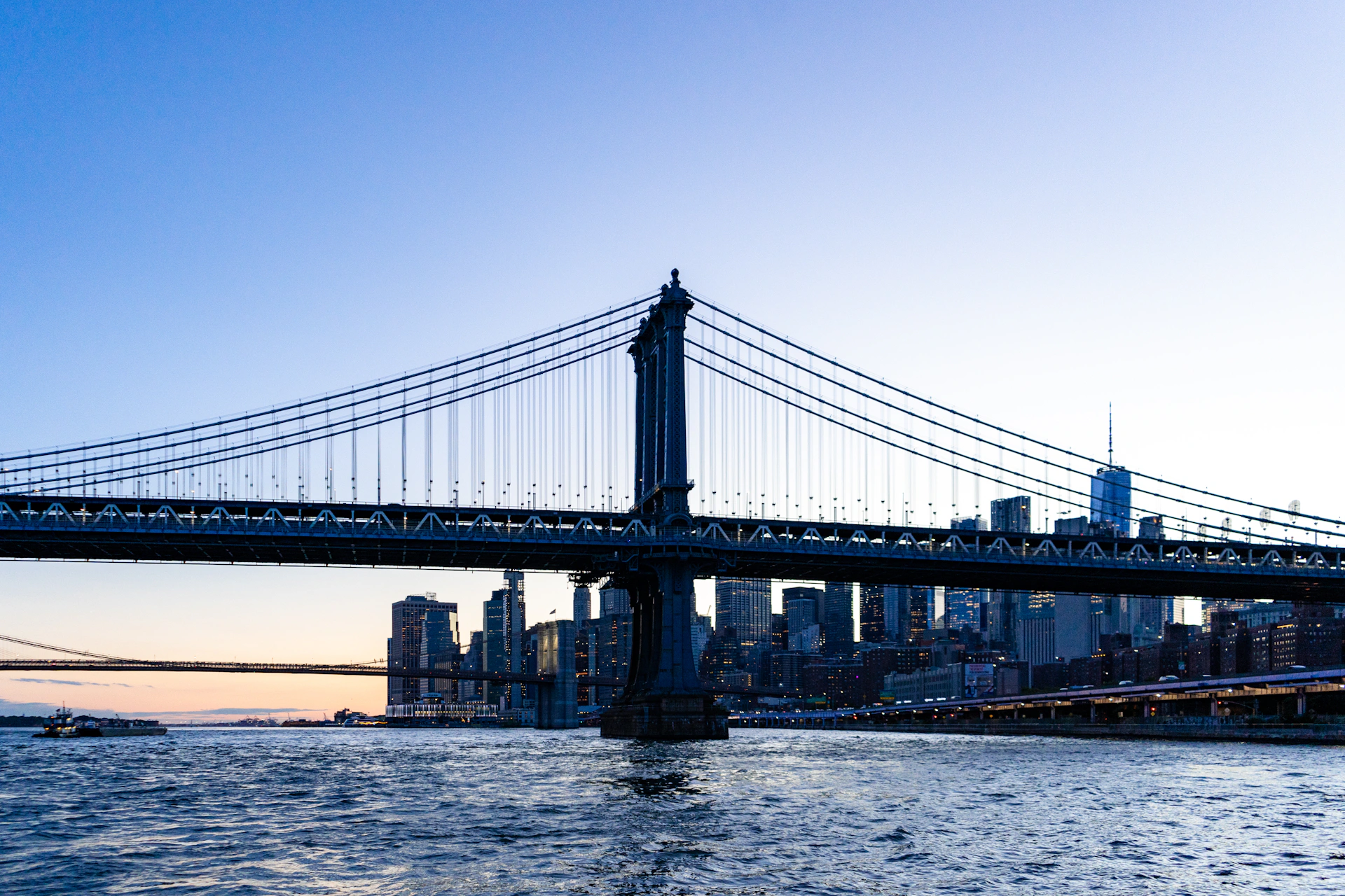 A suspension bridge and city skyline at dusk